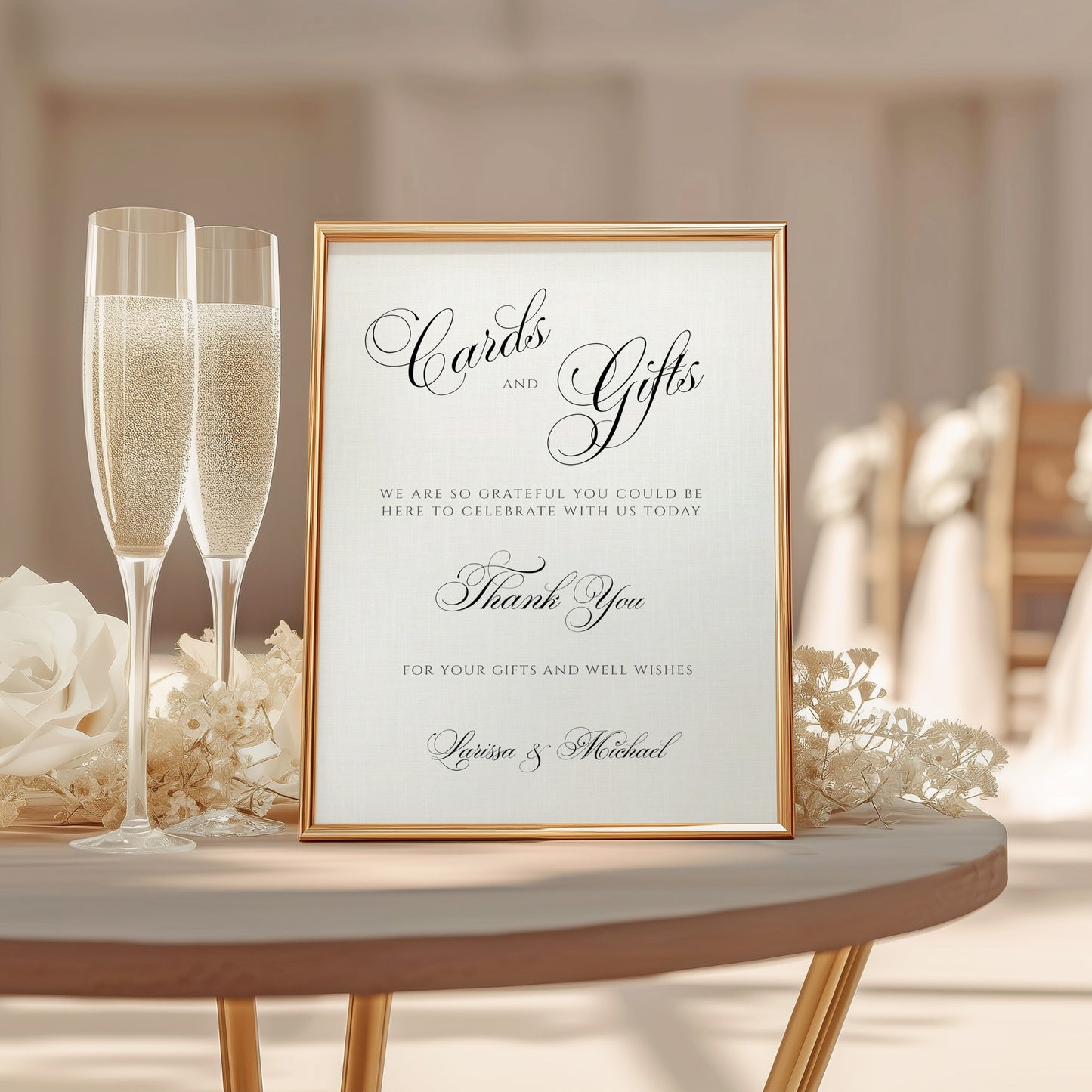 A framed wedding cards and gifts sign with elegant black script on a cream background, styled on a round table with champagne flutes, flowers, and a softly blurred wedding venue in the background.