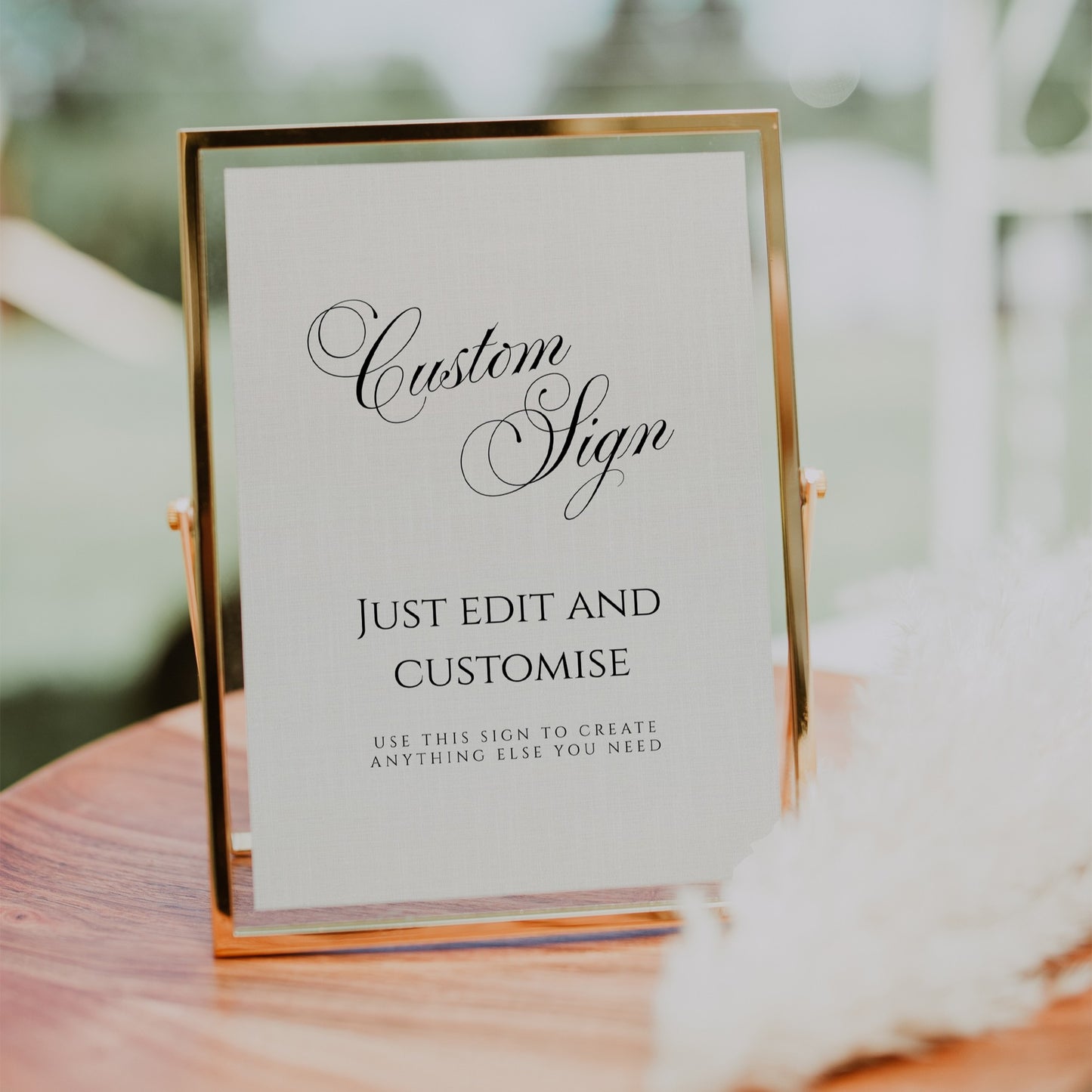 A custom wedding sign in a slim gold metal frame on a small stand, displayed on a wooden surface with a softly blurred indoor background.